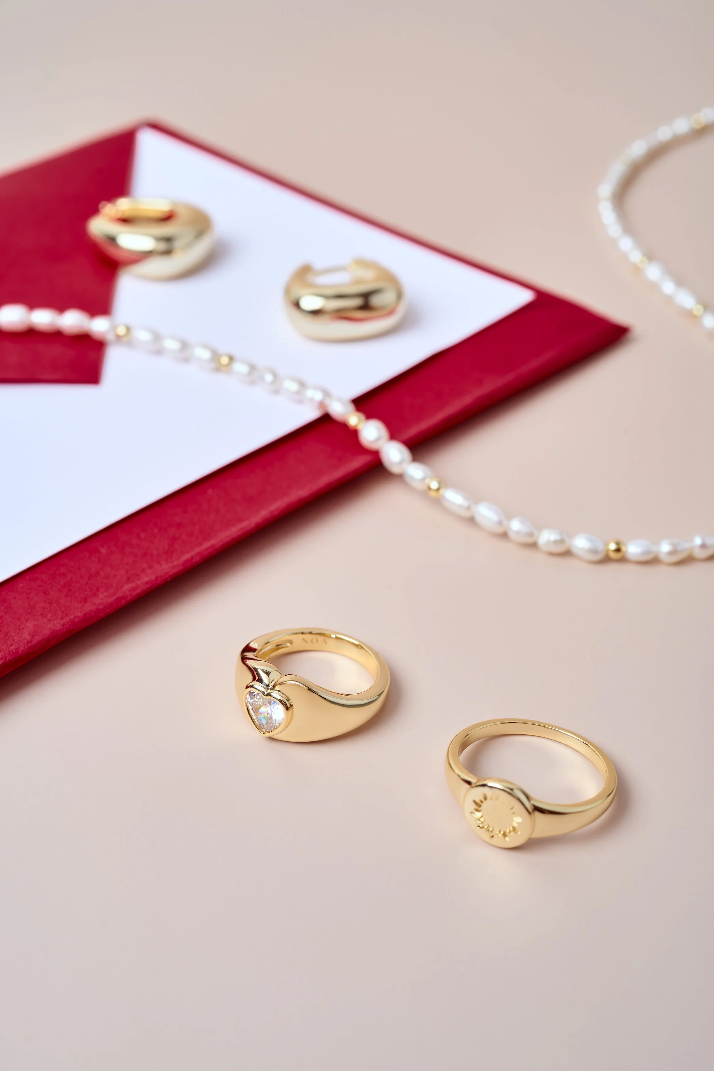fotografia minimalista de producto, fotografía aros, fotografia joyas, dorado, aros, oro, collares, frutillas, perlas