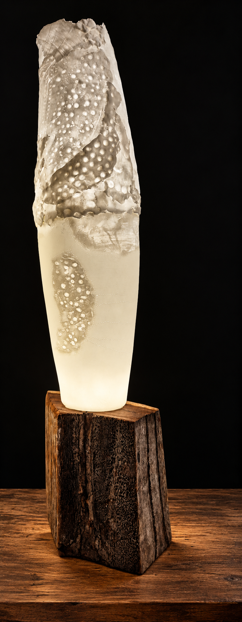 Glowing Textured Glass Sculpture on Wood.png