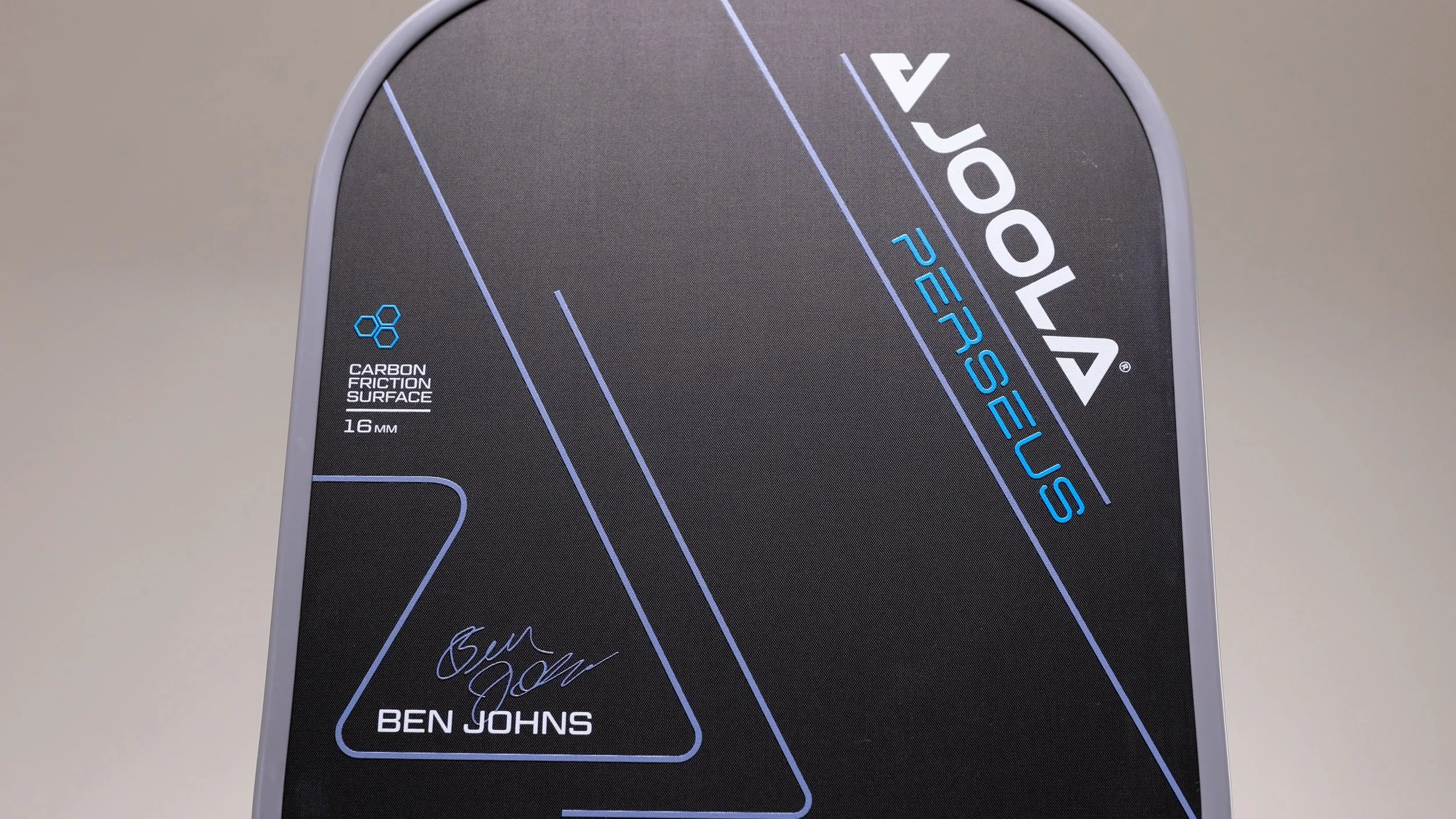 Close-up of JOOLA Ben Johns Perseus 16mm pickleball paddle face showing Carbon Friction Surface and Ben Johns signature