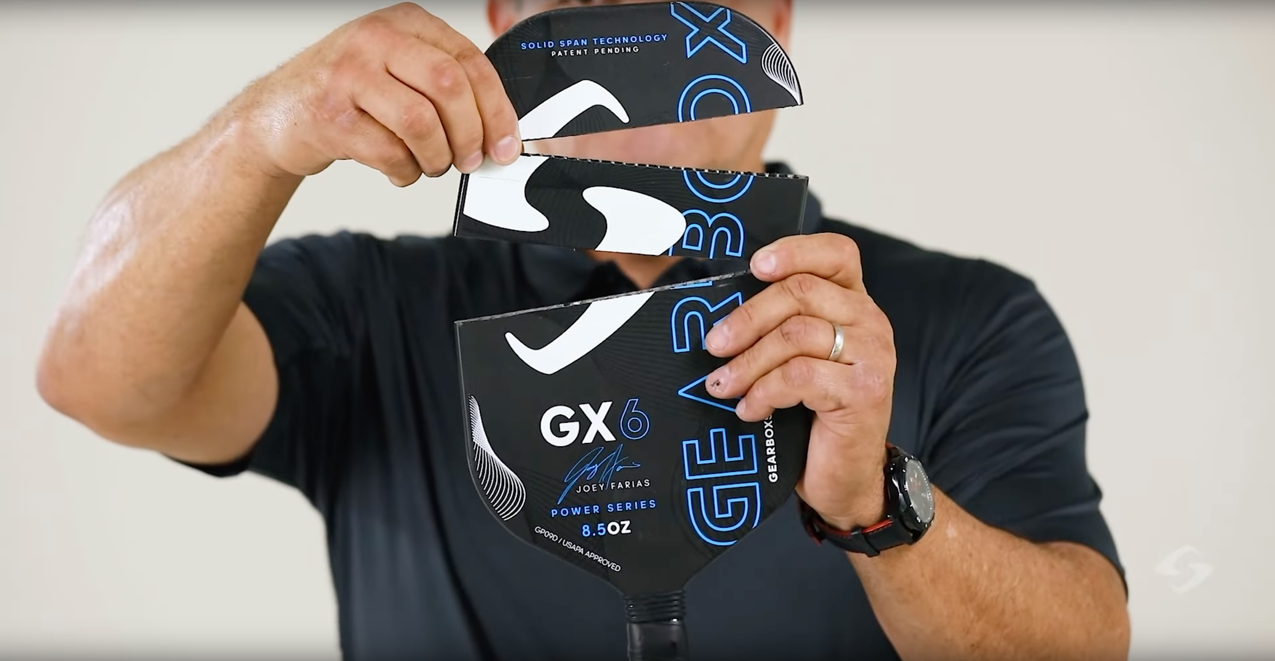 Person peeling carbon fiber face layer off a Gearbox GX6 pickleball paddle