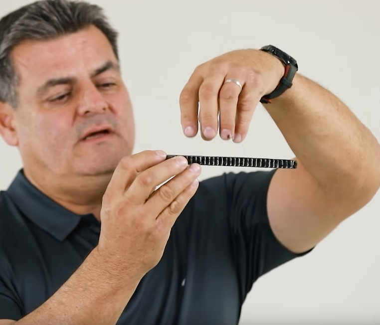 Person examining a strip of carbon fiber material from a pickleball paddle