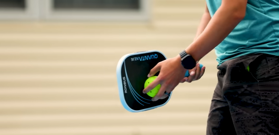 Player holding Ronbus Quanta pickleball paddle with ball during outdoor court play test
