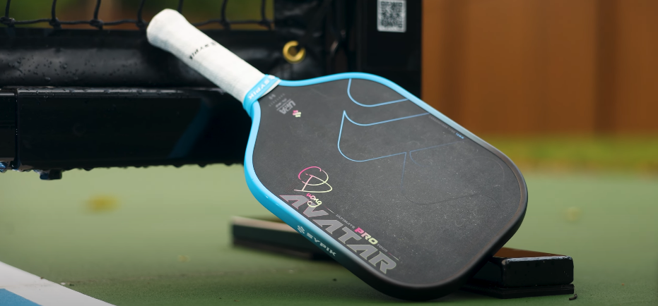 Sypik Avatar pickleball paddle with blue accents resting on outdoor pickleball court