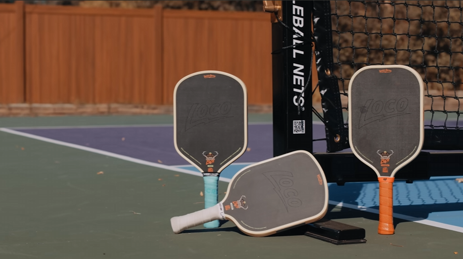 Bread & Butter Loco pickleball paddles in three shapes displayed courtside against a net