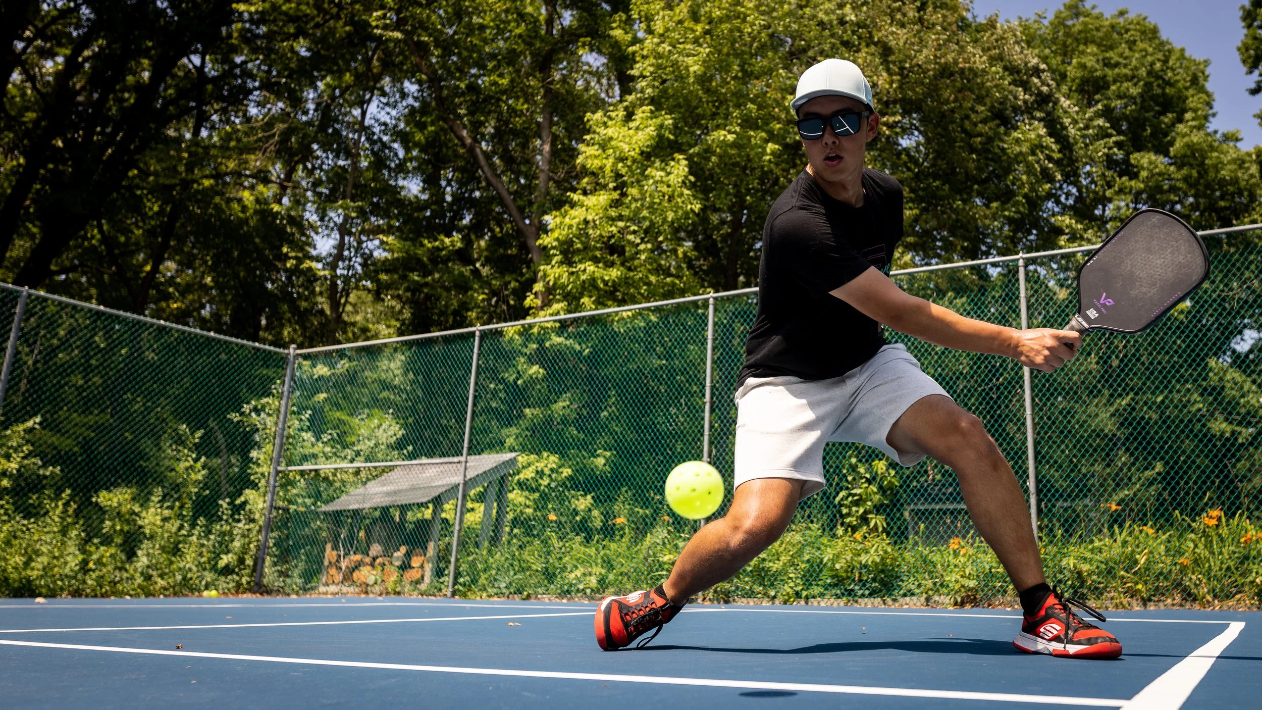Player hitting a backhand with the Vatic Pro Prism pickleball paddle on an outdoor court