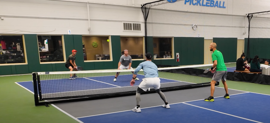 Players competing in a pickleball doubles match on an indoor court