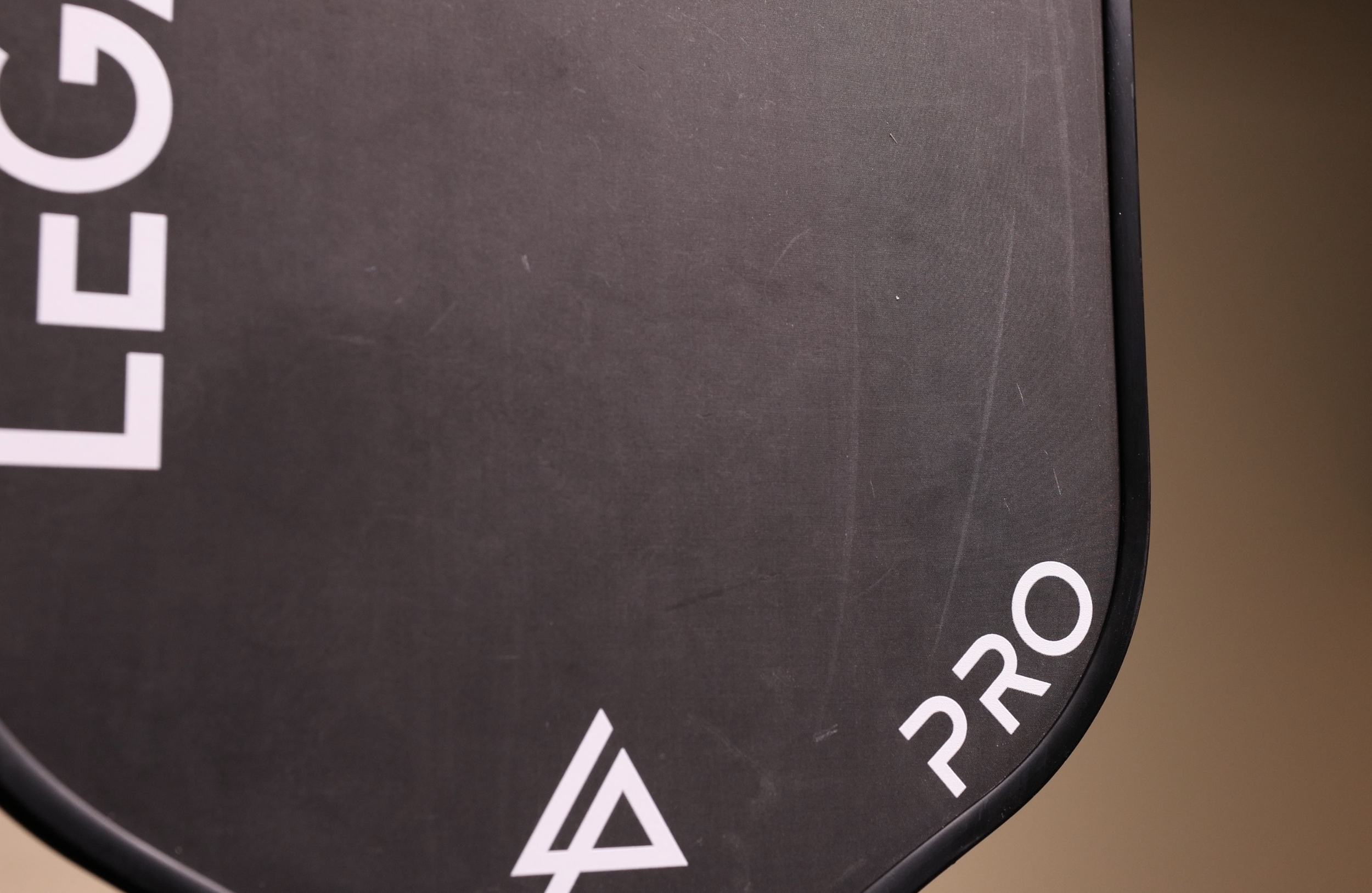 Legacy Pro pickleball paddle bottom edge close-up showing logo and surface condition after use
