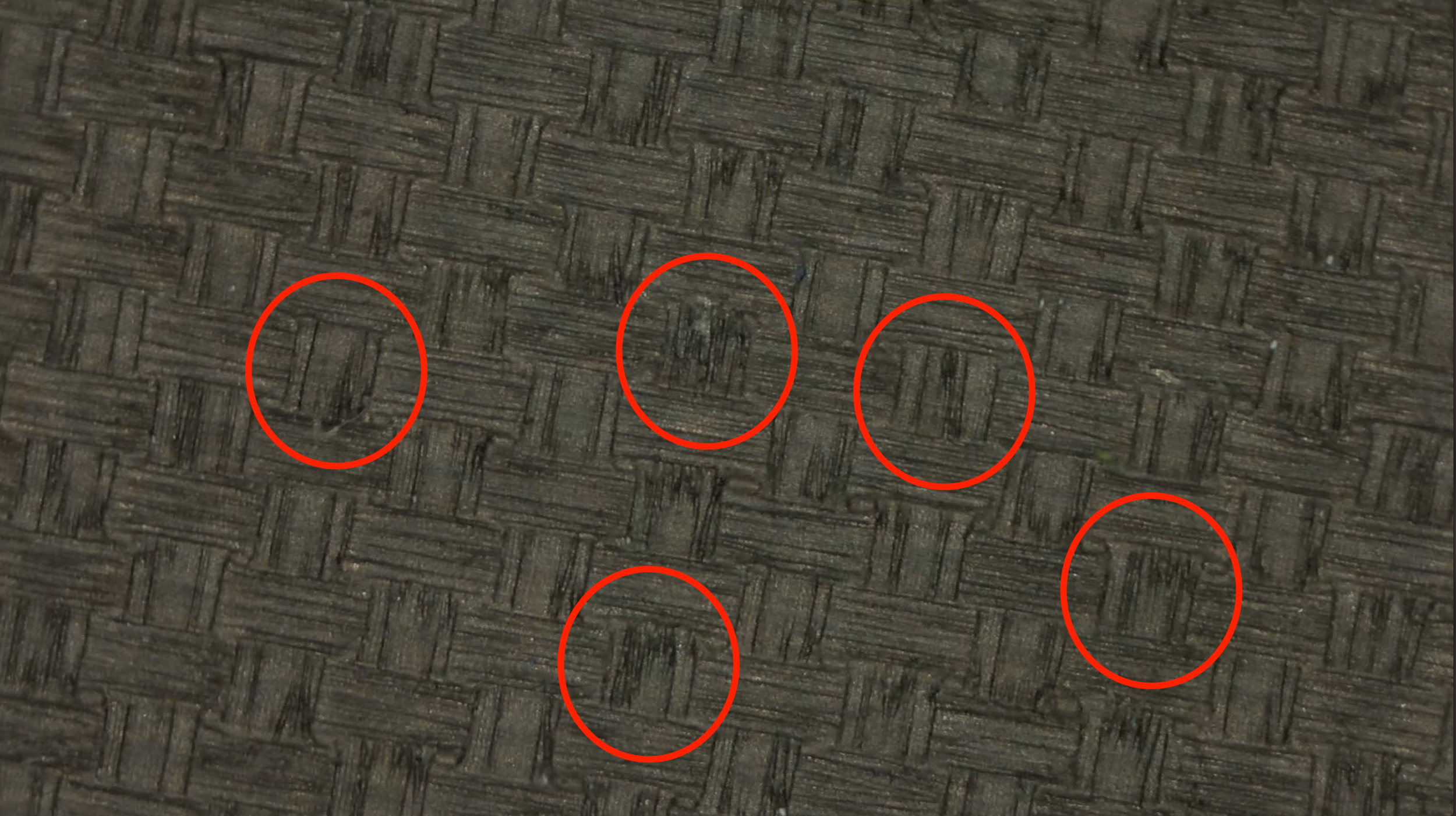 Macro close-up of JOOLA Hyperion CFS pickleball paddle carbon fiber surface with red circles highlighting texture imperfections