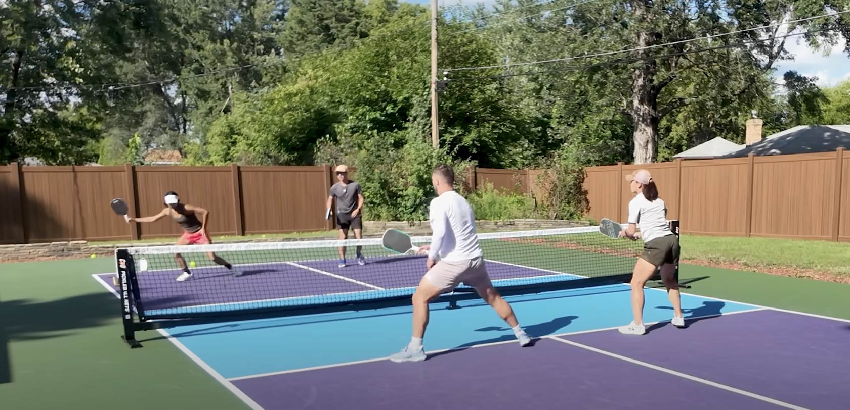 Four players playing doubles pickleball on an outdoor backyard court testing Ronbus Quanta paddles