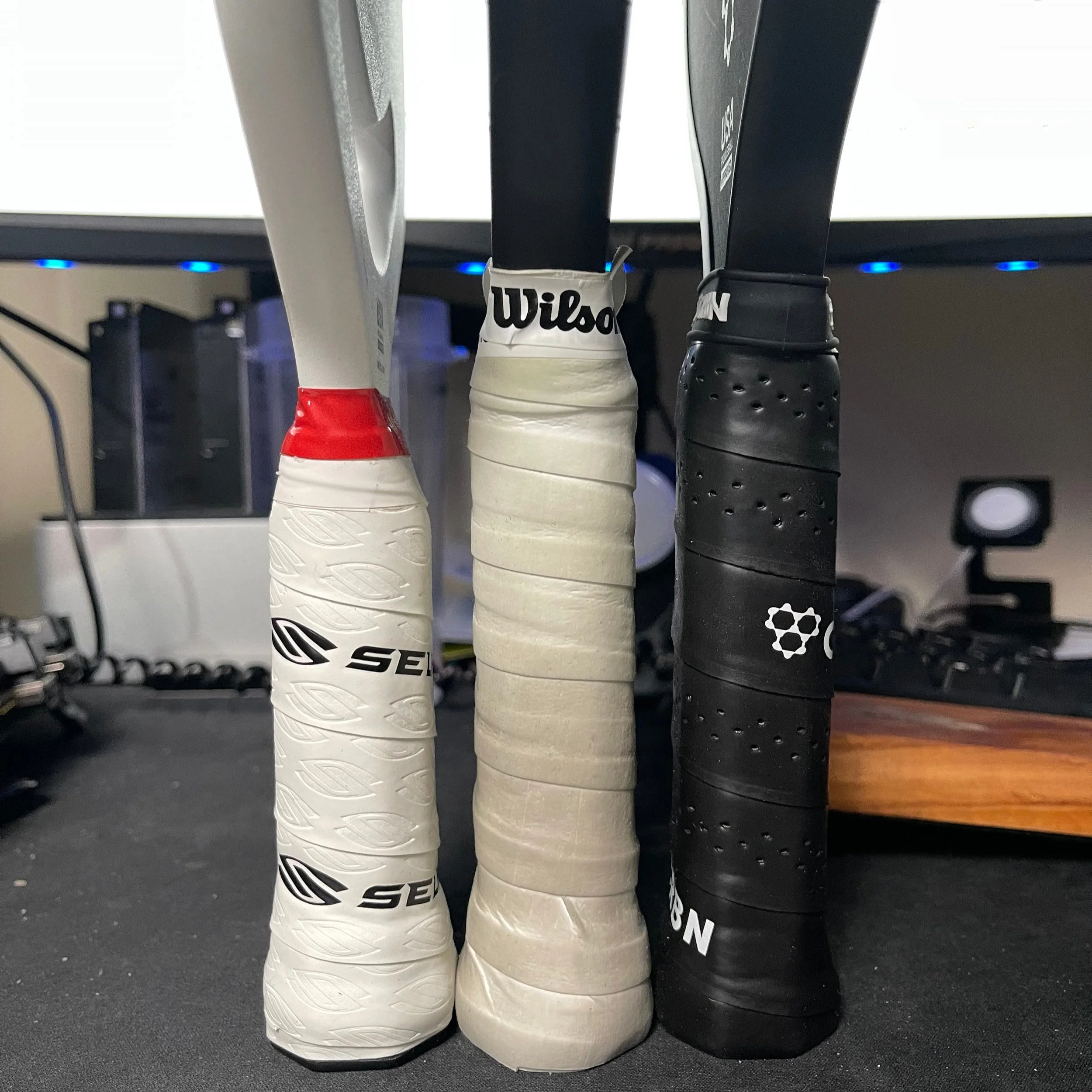 Three pickleball paddle handles compared side by side including Selkirk Wilson and CRBN grips
