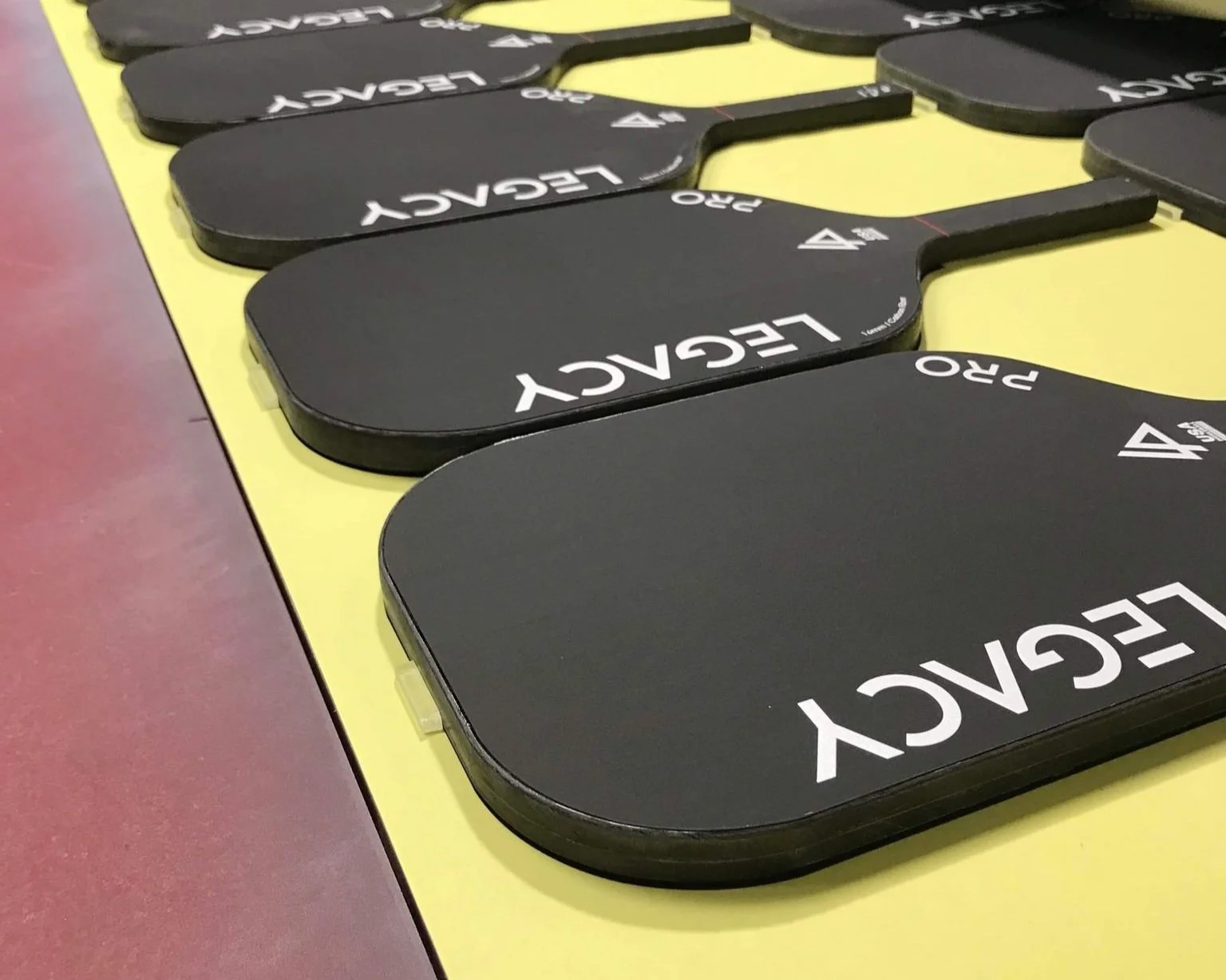 Legacy Pro pickleball paddles lined up on a table showing multiple units in black colorway
