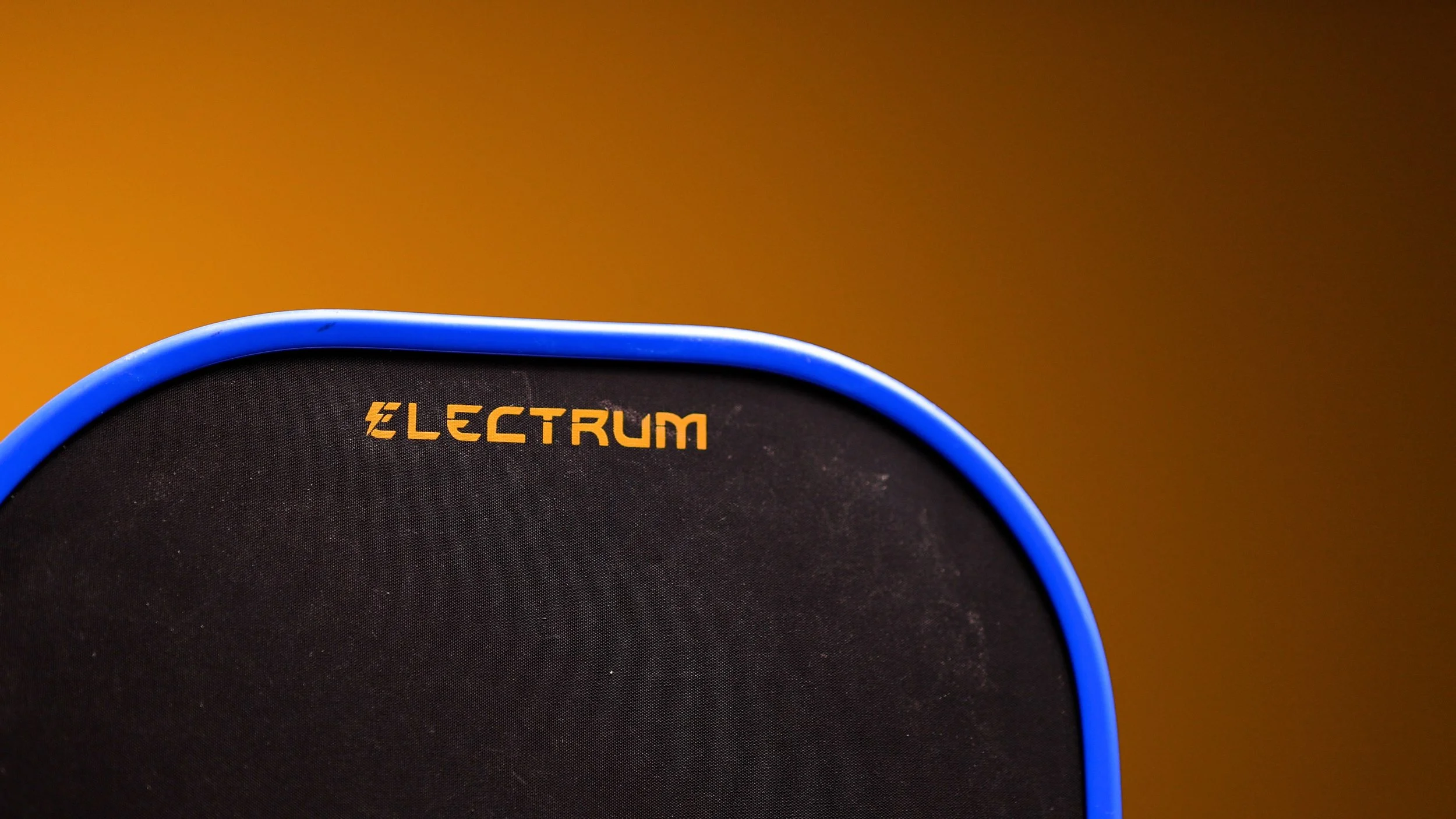 Electrum pickleball paddle top edge showing Electrum branding and carbon fiber face texture