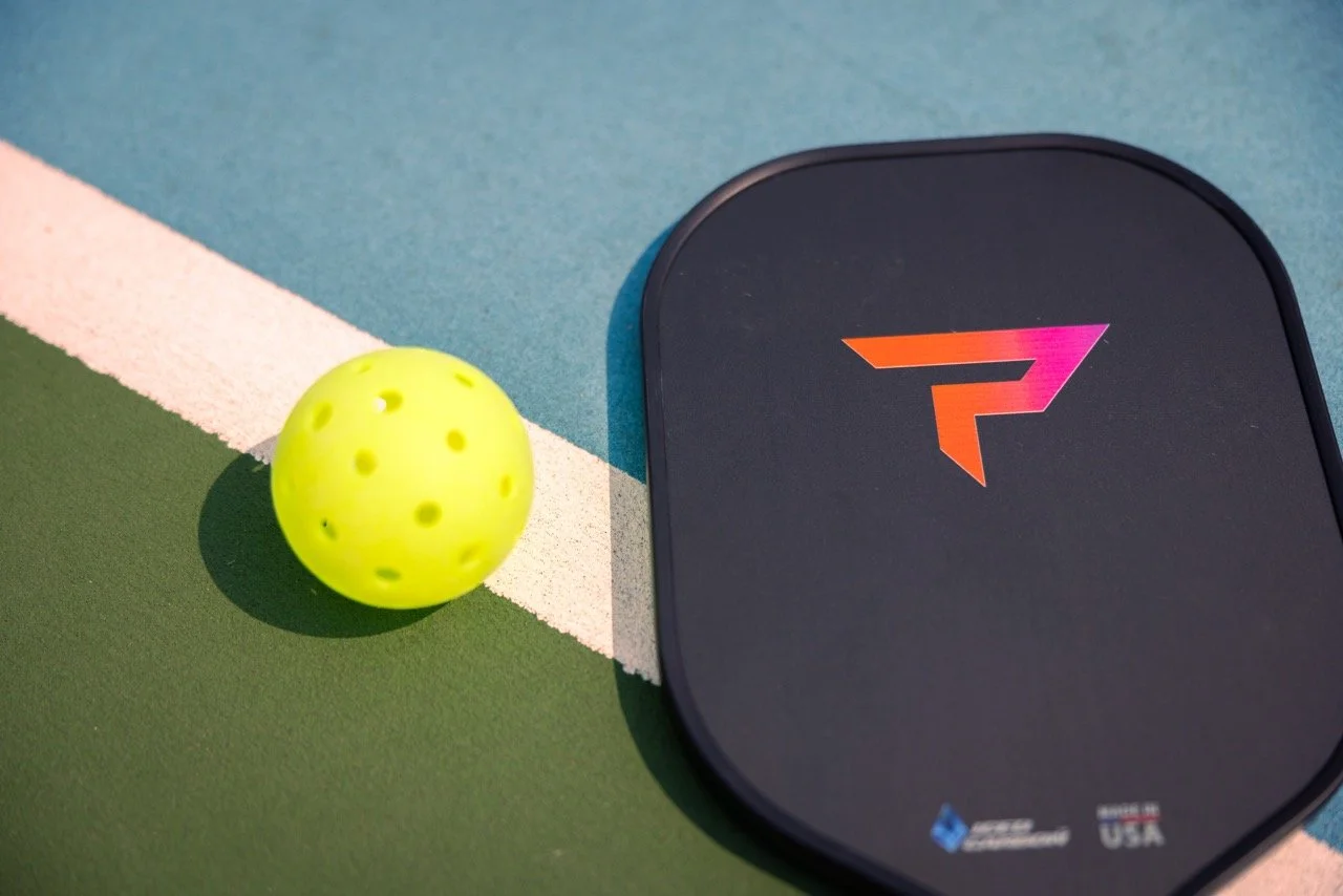 PaddleTek Tempest Wave v3 pickleball paddle on court with pickleball ball beside it