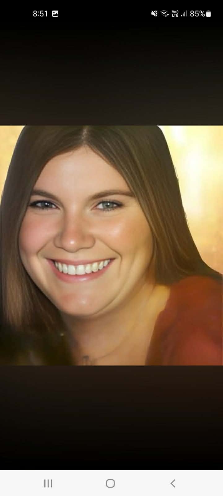 Portrait of a smiling woman with brown hair and blue eyes, wearing a maroon top.