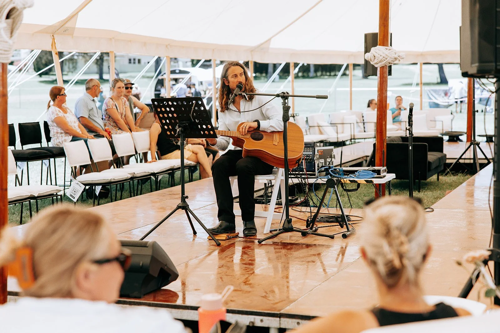 Musician performing with acoustic guitar under tent at event