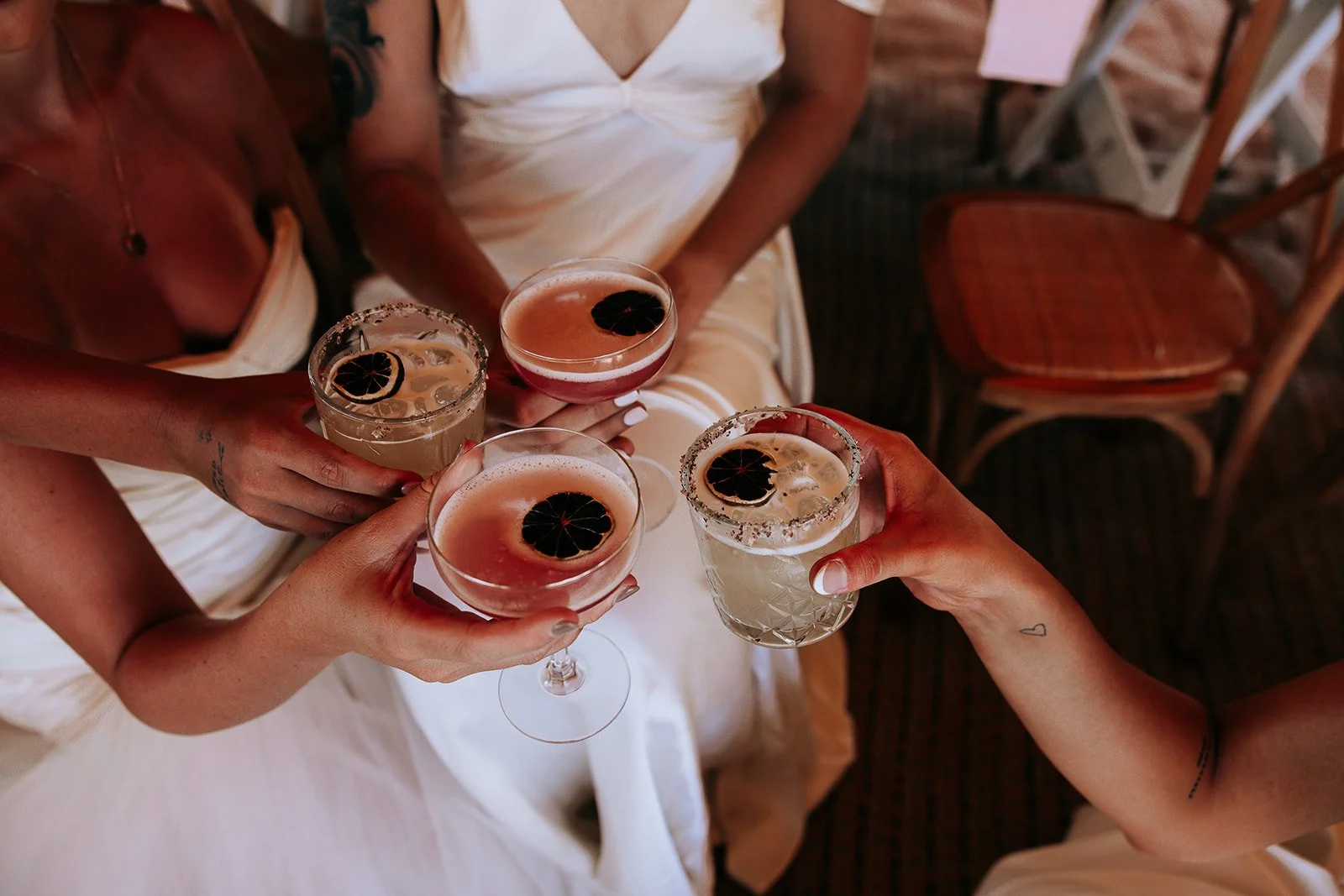 People in white dresses holding cocktails with sliced lime garnishes.