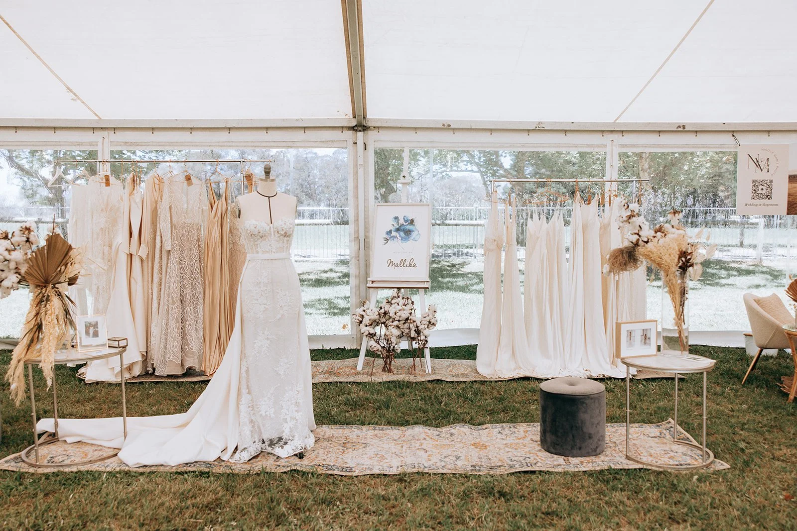 Bridal boutique showcase with wedding dresses and decor in a tent setting.