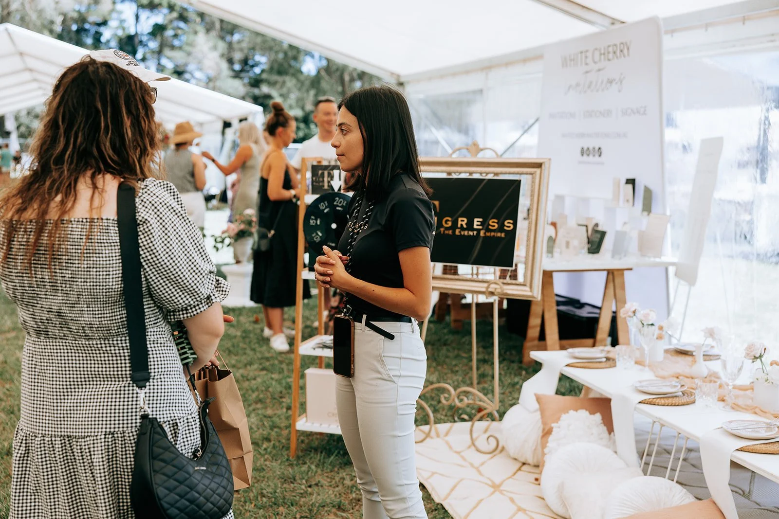 People interacting at a wedding expo booth, featuring event planning displays and decor.