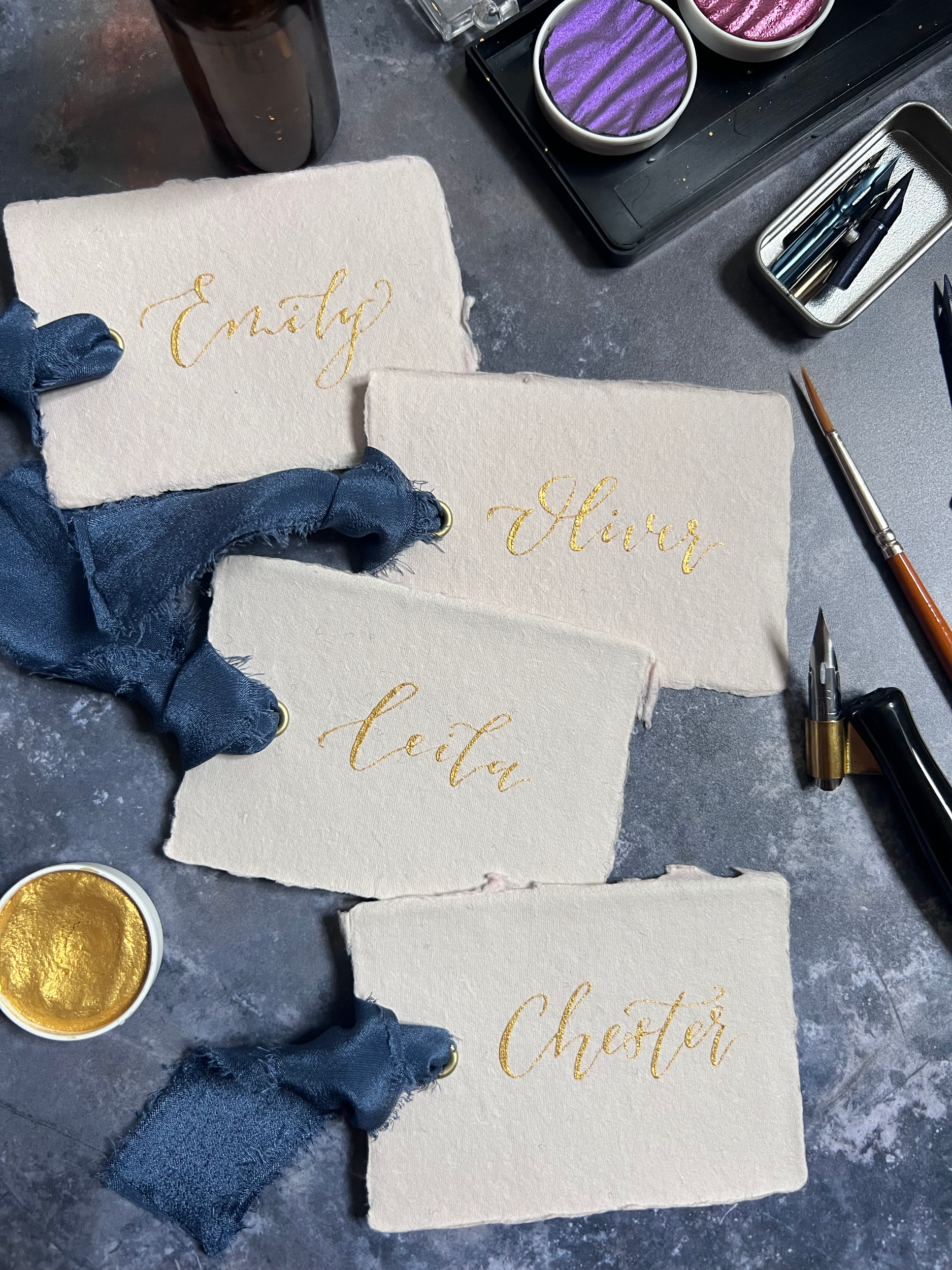 Handmade paper place names with luxury blue silk ribbon and gold calligraphy