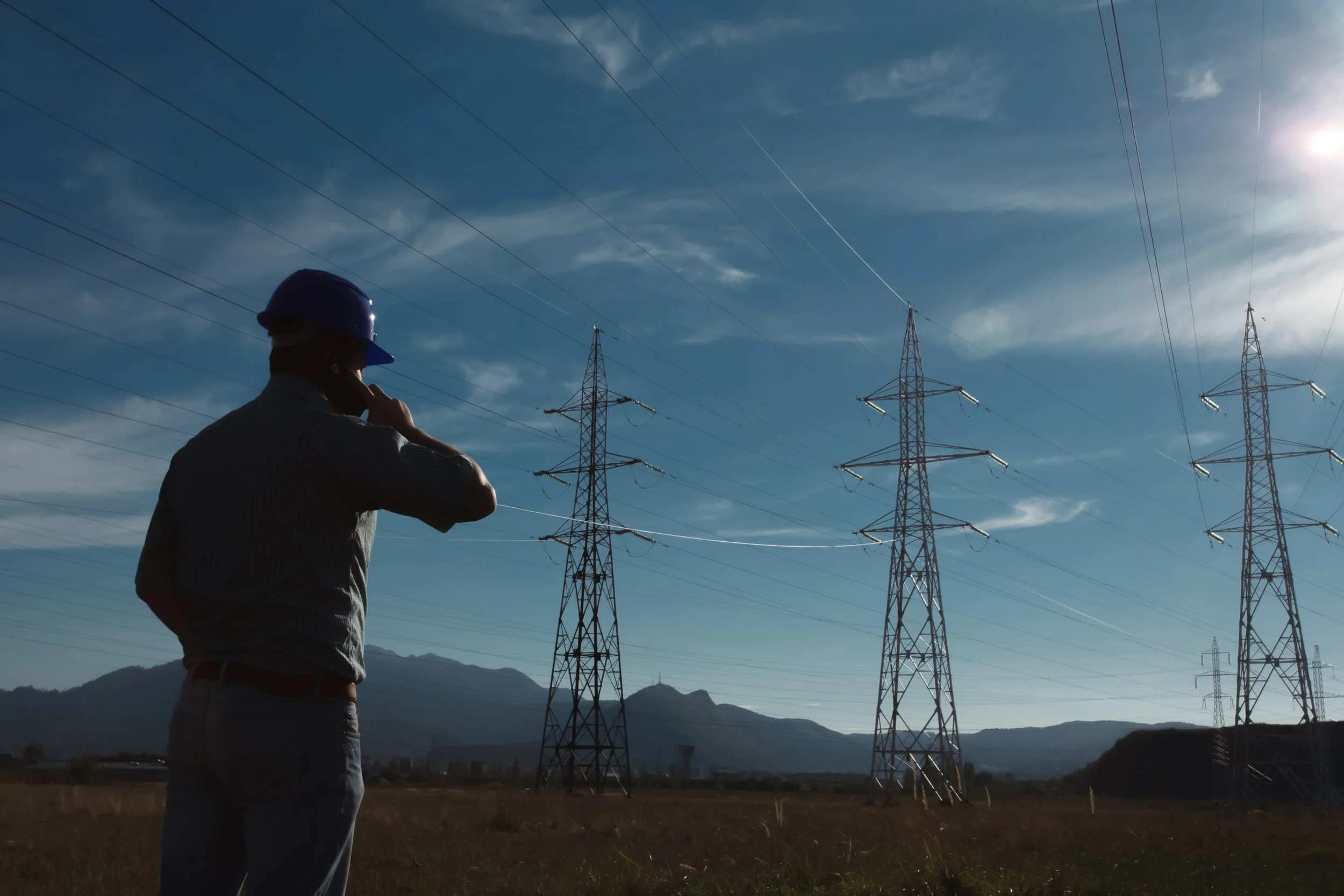 An engineer in the foreground with electricity pylons in the distance