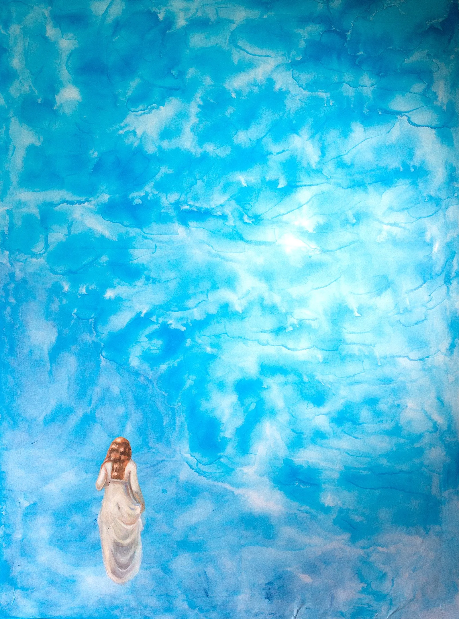 Female figure seen from behind standing before a large textured blue expanse.