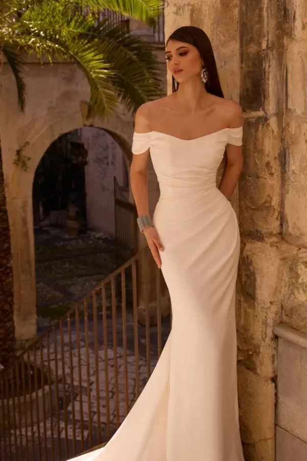 Bride in a wedding dress with a long train, standing in a dark wood-paneled room.