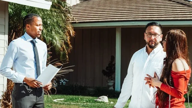 Real estate agent with documents talking to a potential buyer outside a house