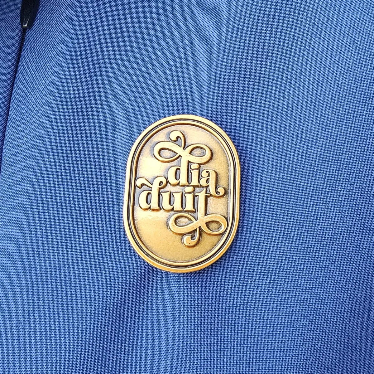 The Dia Duit pin on a navy-blue jacket
