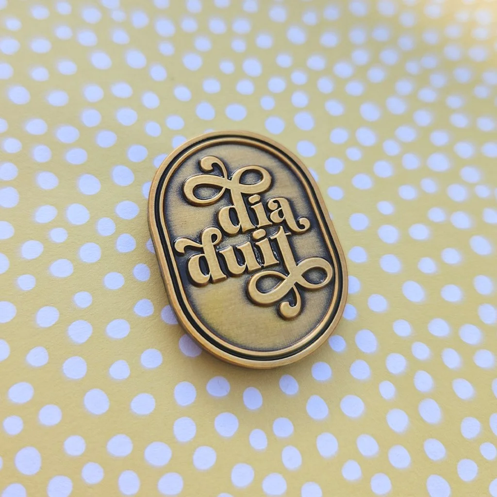 A Dia Duit pin against a bright, polka dot background