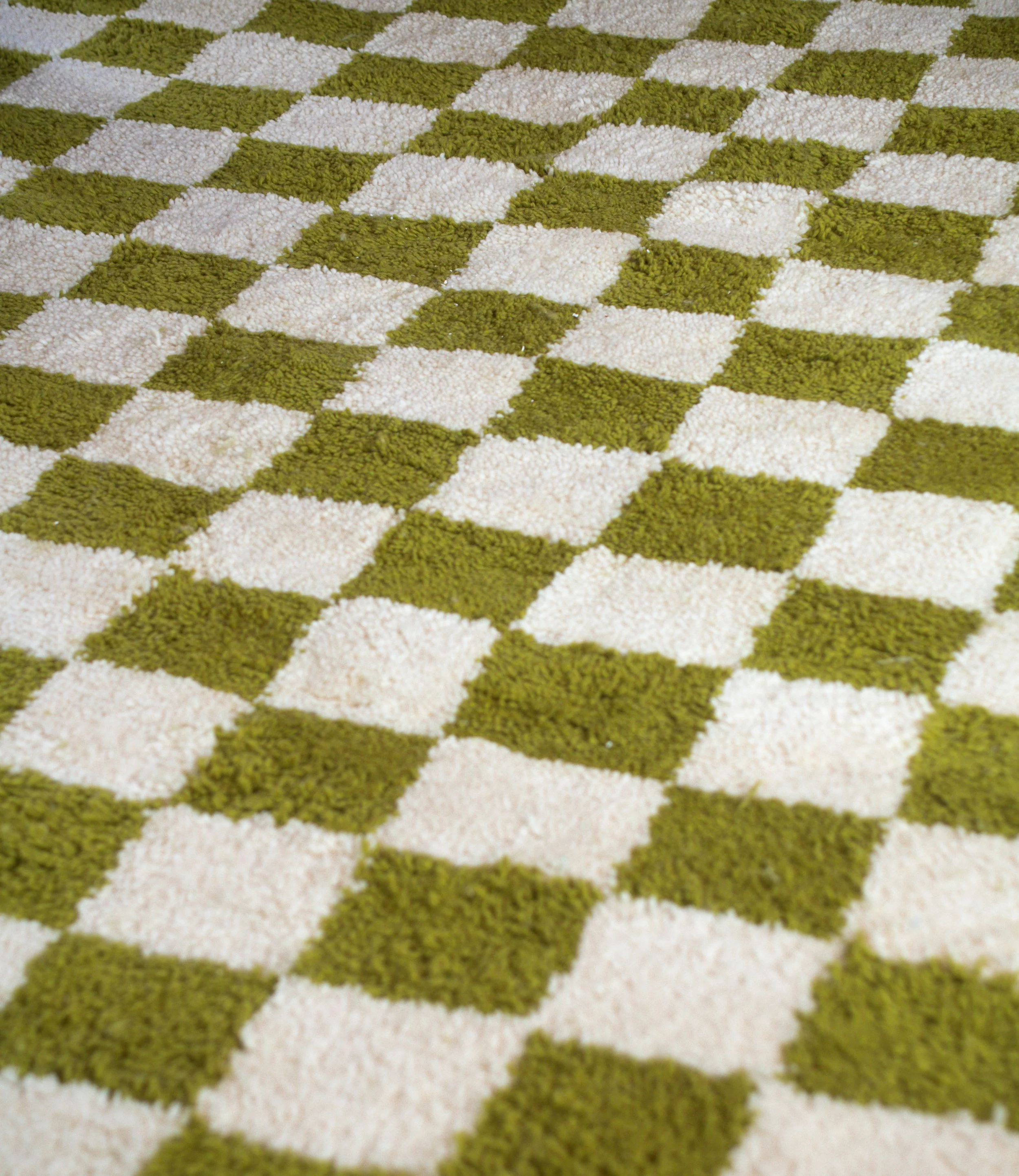 Close-up of a checkered shaggy rug with alternating green and cream-colored squares.