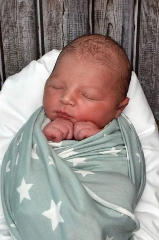 Newborn baby wrapped in a star-patterned blanket, sleeping.