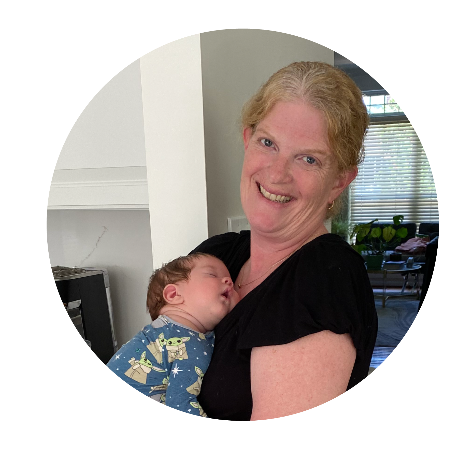 Woman smiling holding a sleeping baby