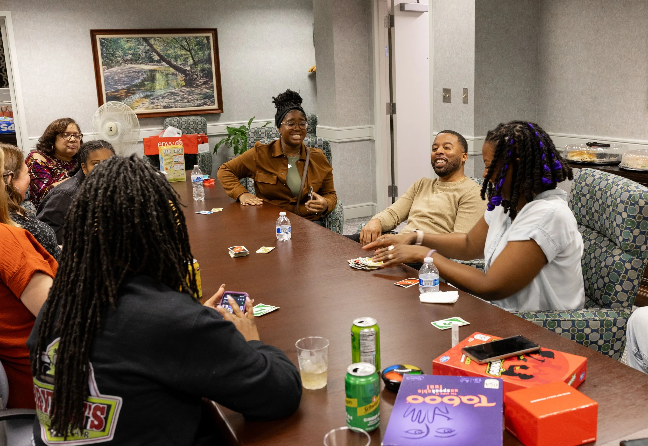 Group of game night attendees laughing, playing Uno and connecting