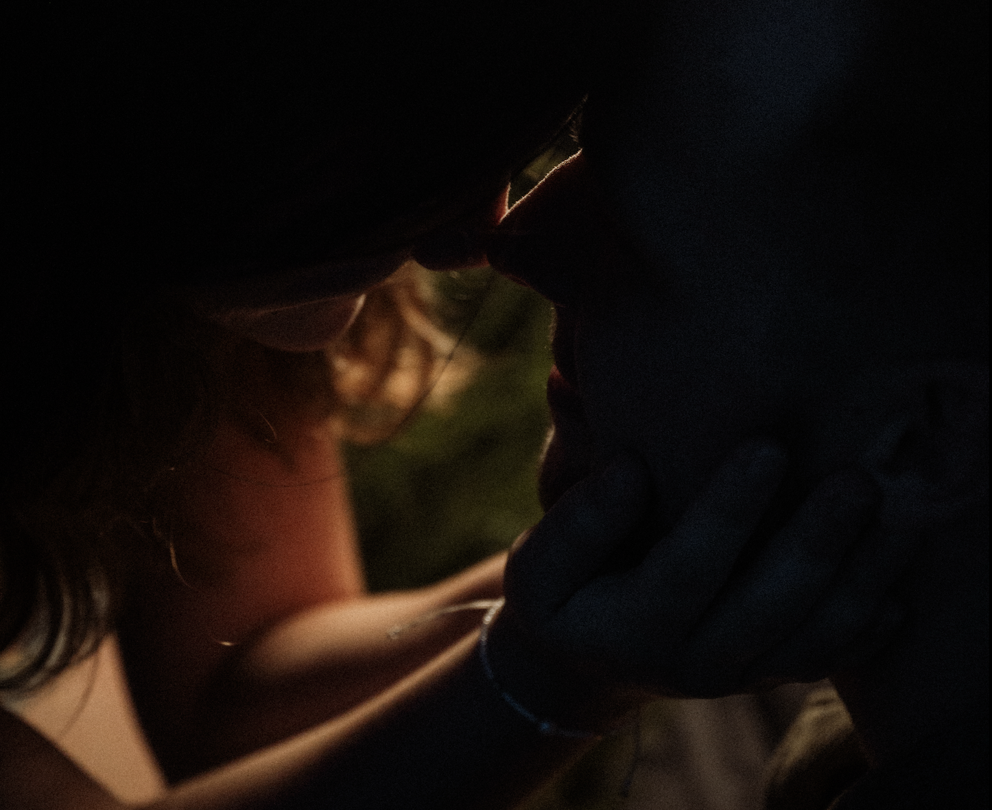 A close-up of a couple kissing in low light, with the woman's face partially visible and the man's face mostly shadowed.