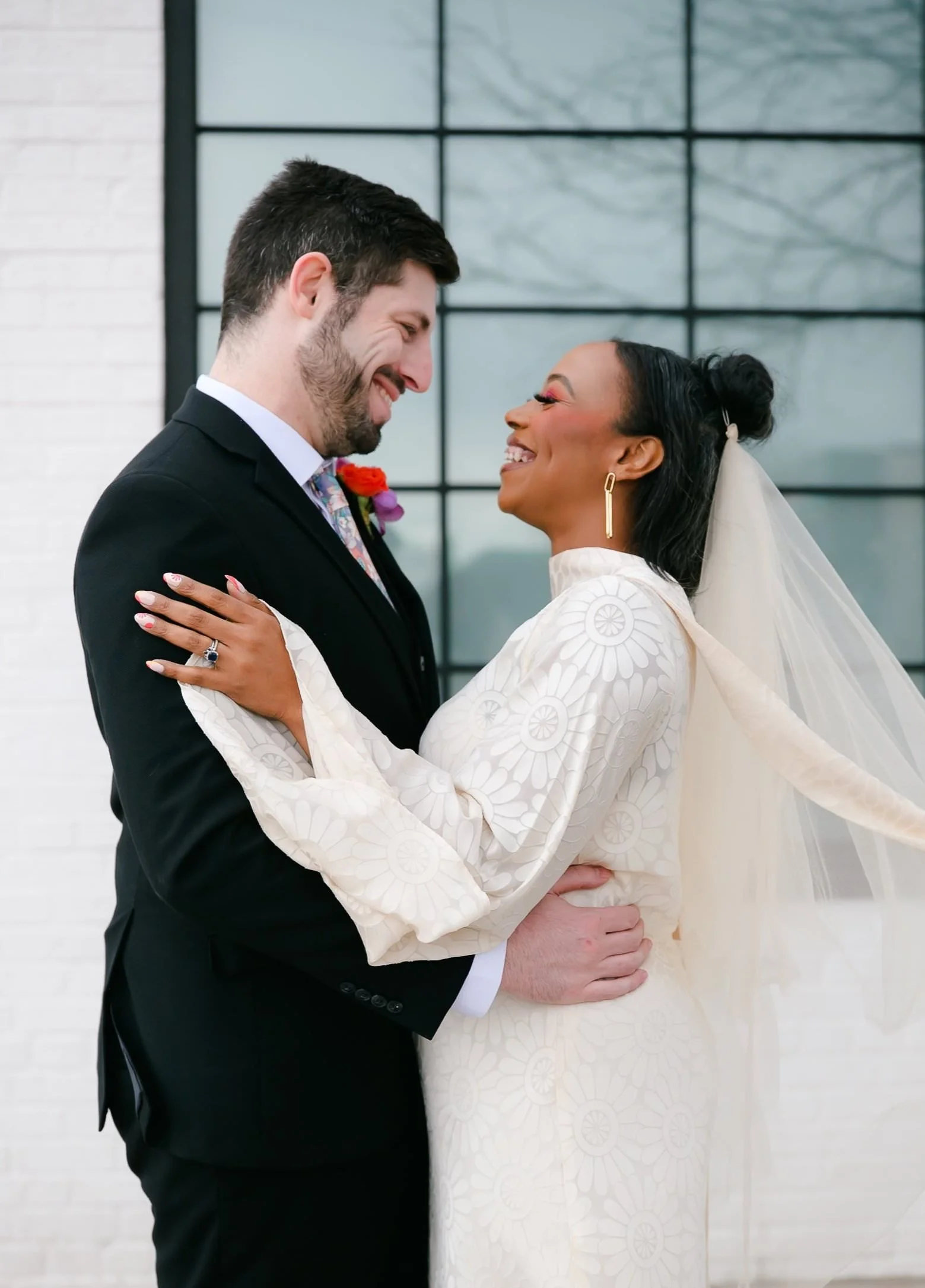 A photo of a BIPOC couple, a man and a black woman smiling and embracing during their denver wedding photo session at dry clean only, a wedding venue in downtown denver colorado