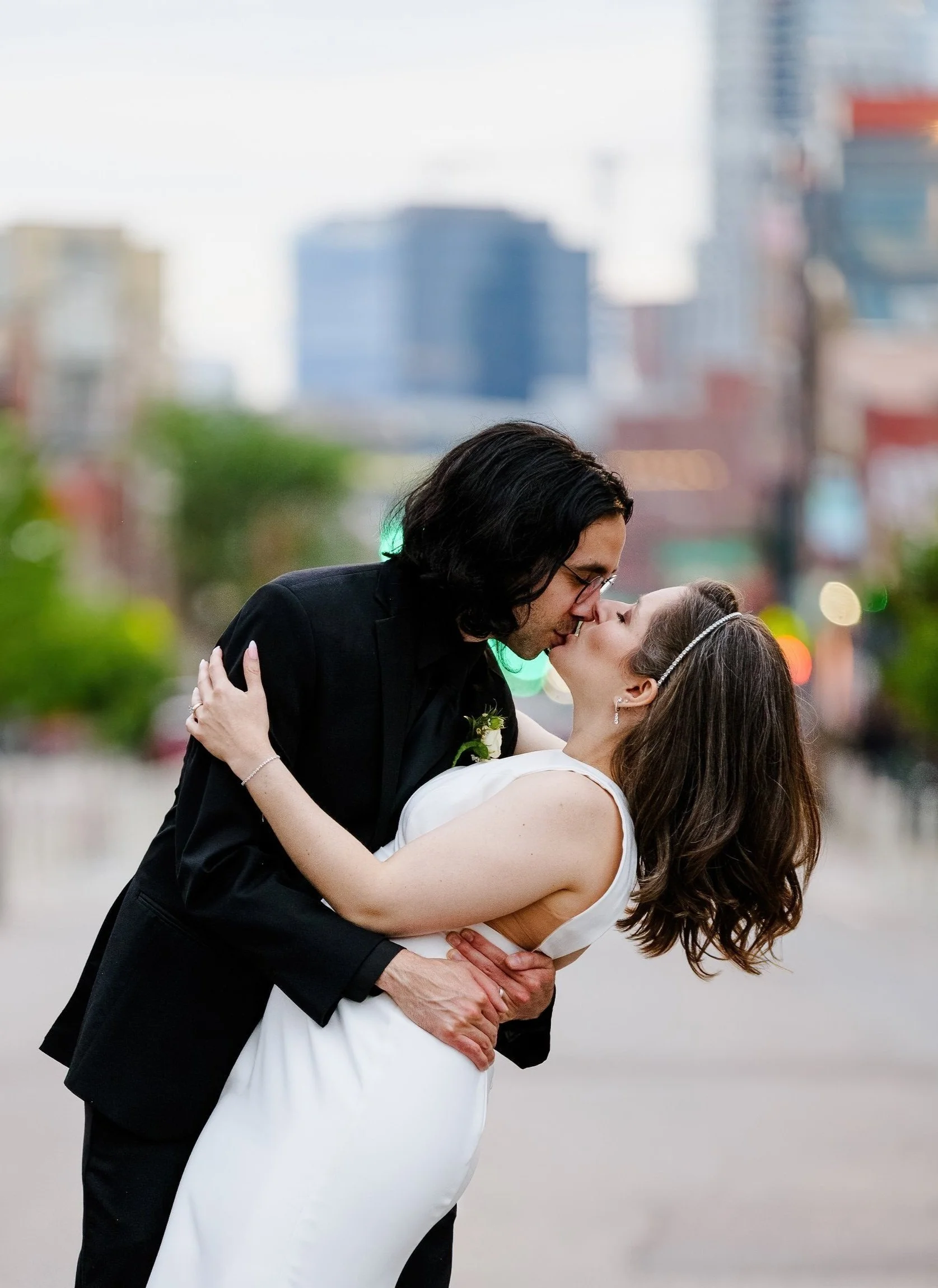 Among the denver streets near the art museum a married couple shares a kiss after getting married in Denver, Colorado