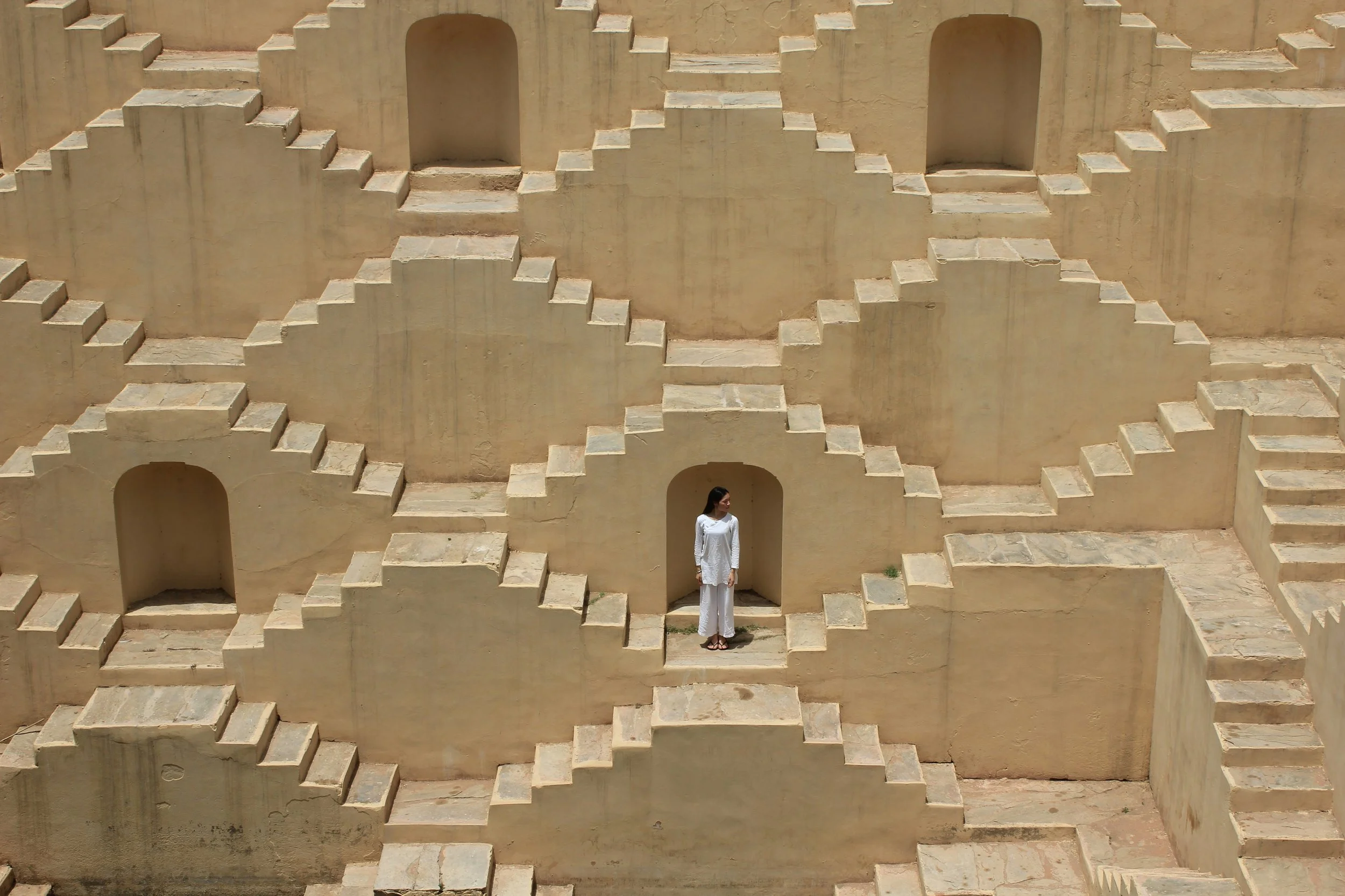 Person standing within an ancient stepped stone structure, symbolising the journey of Qigong Teacher Training, embodiment, mentorship and the path beyond accreditation.