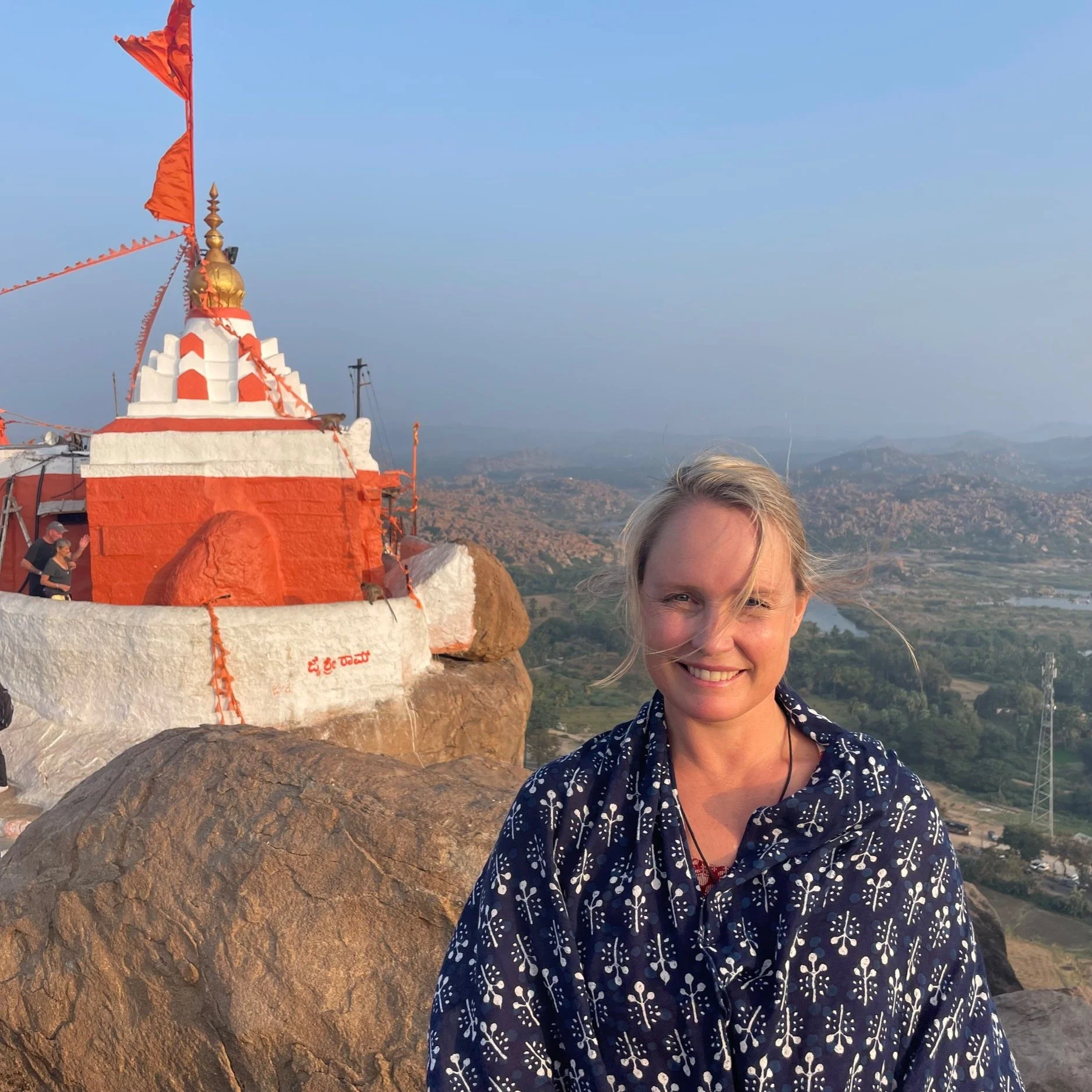 Nicole Lee standing beside a red and white temple overlooking a landscape in India
