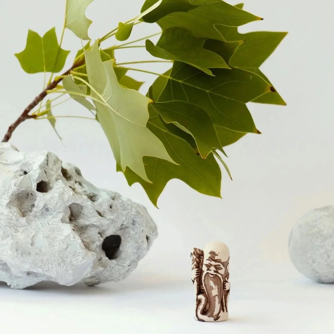 Green leaves, natural stone and a small Daoist figure arranged in a still life