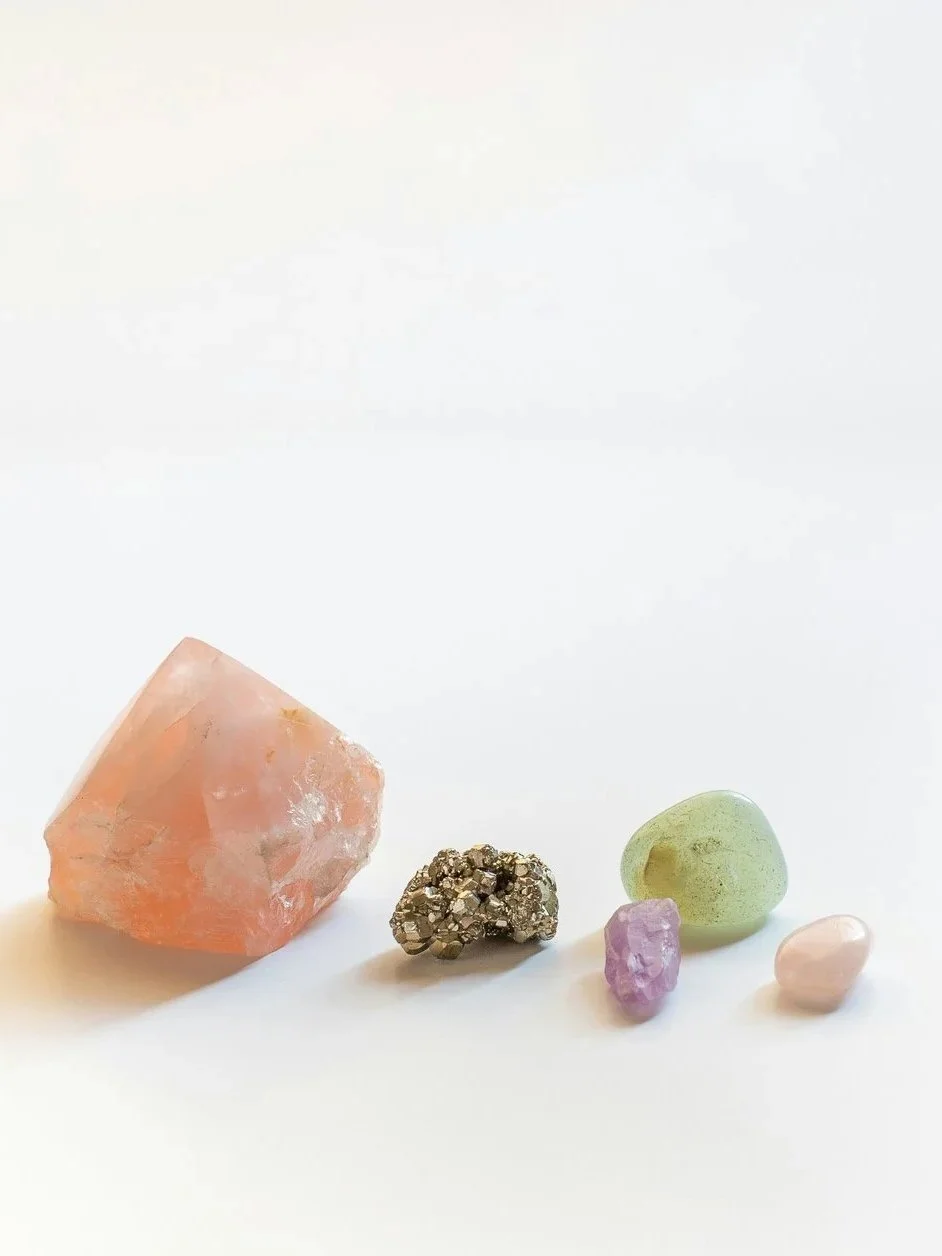 Five natural stones in different shapes, colours and textures arranged together on a white surface.