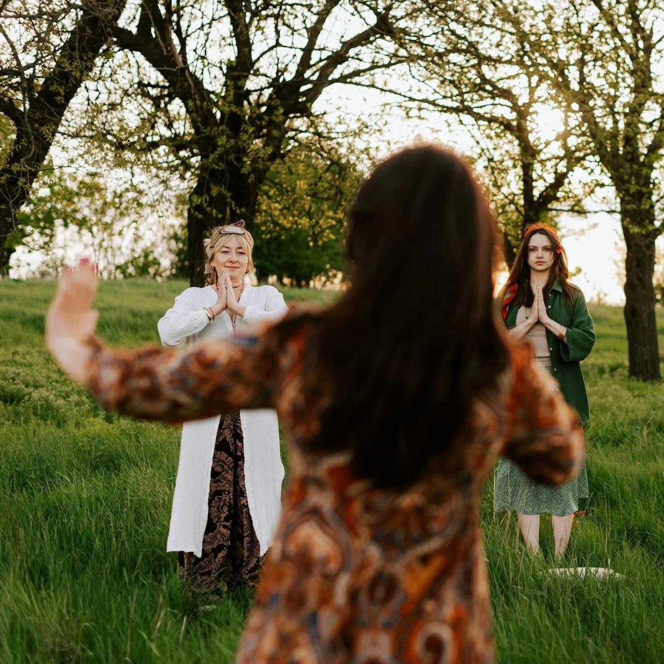 Qigong teacher guiding two women through practice outdoors