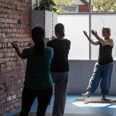 Qigong teacher guiding students through a standing practice in a small group setting