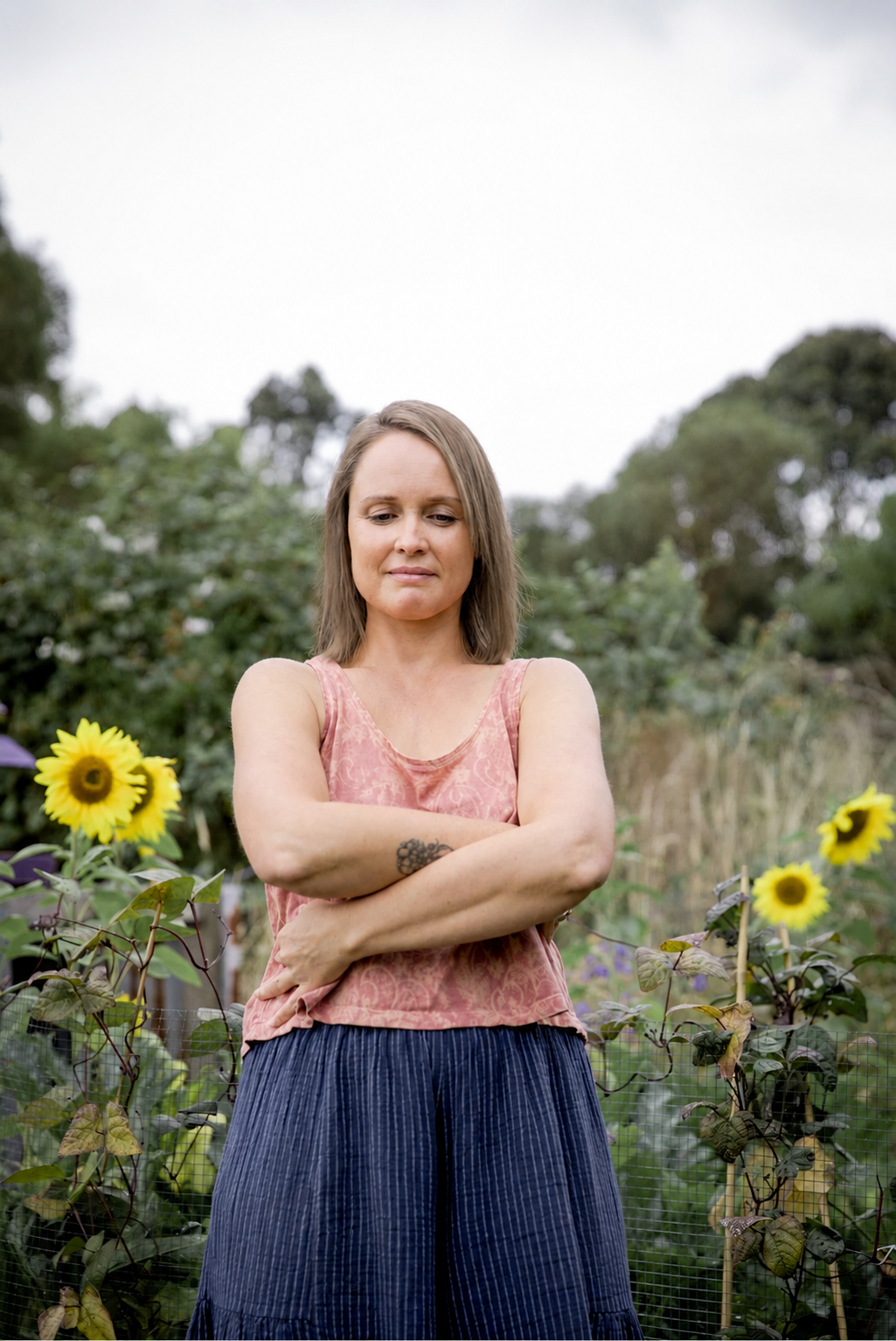 Woman practising Qigong outdoors in a garden surrounded by sunflowers
