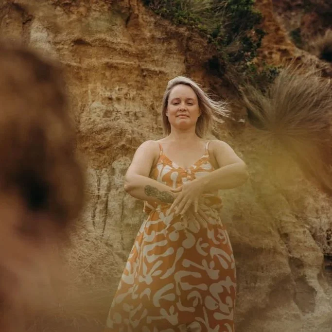 Woman practising Qigong outdoors surrounded by sandstone and native vegetation