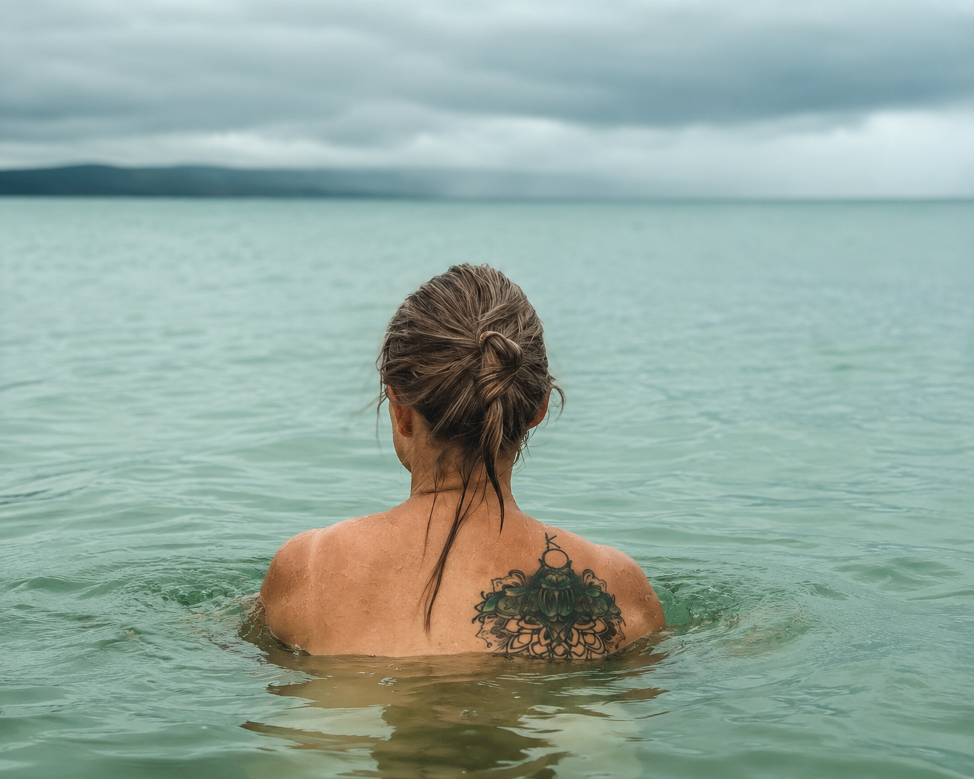 Nicole standing quietly in the ocean, reflecting on nature, stillness and our relationship with life.