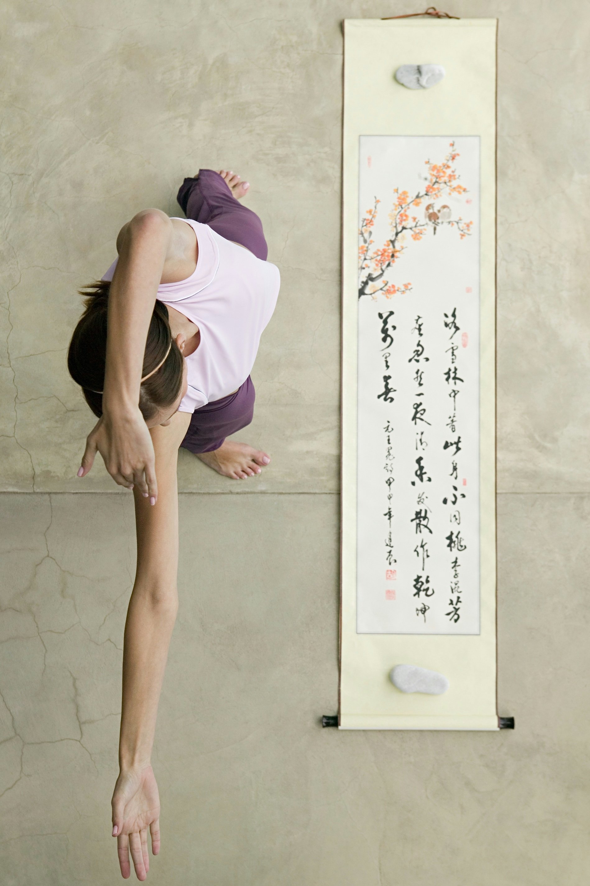 Person practicing Qigong stretching movement indoors, focusing on flexibility and body awareness.