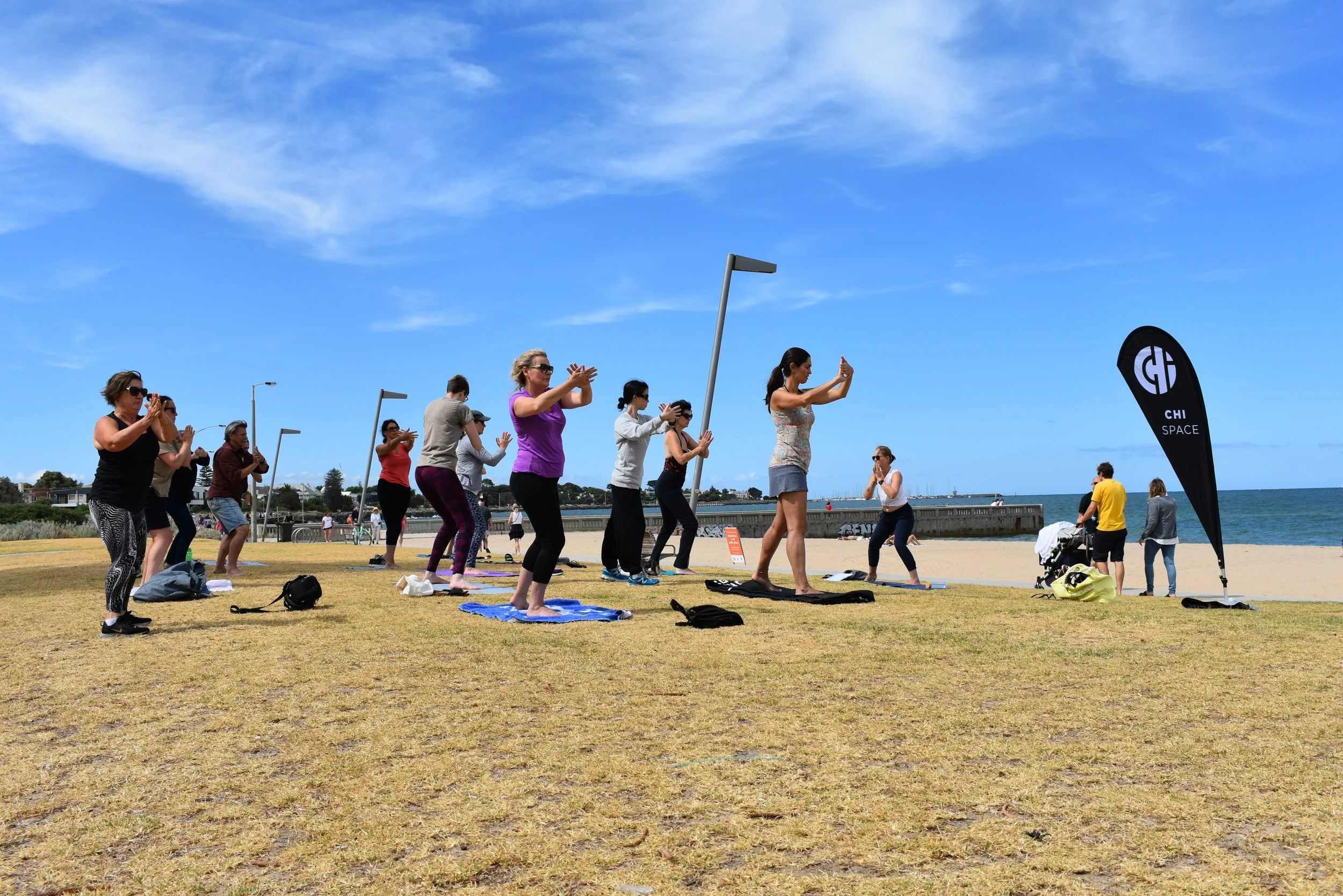 Qigong teacher leading students through a group Qigong practice outdoors.