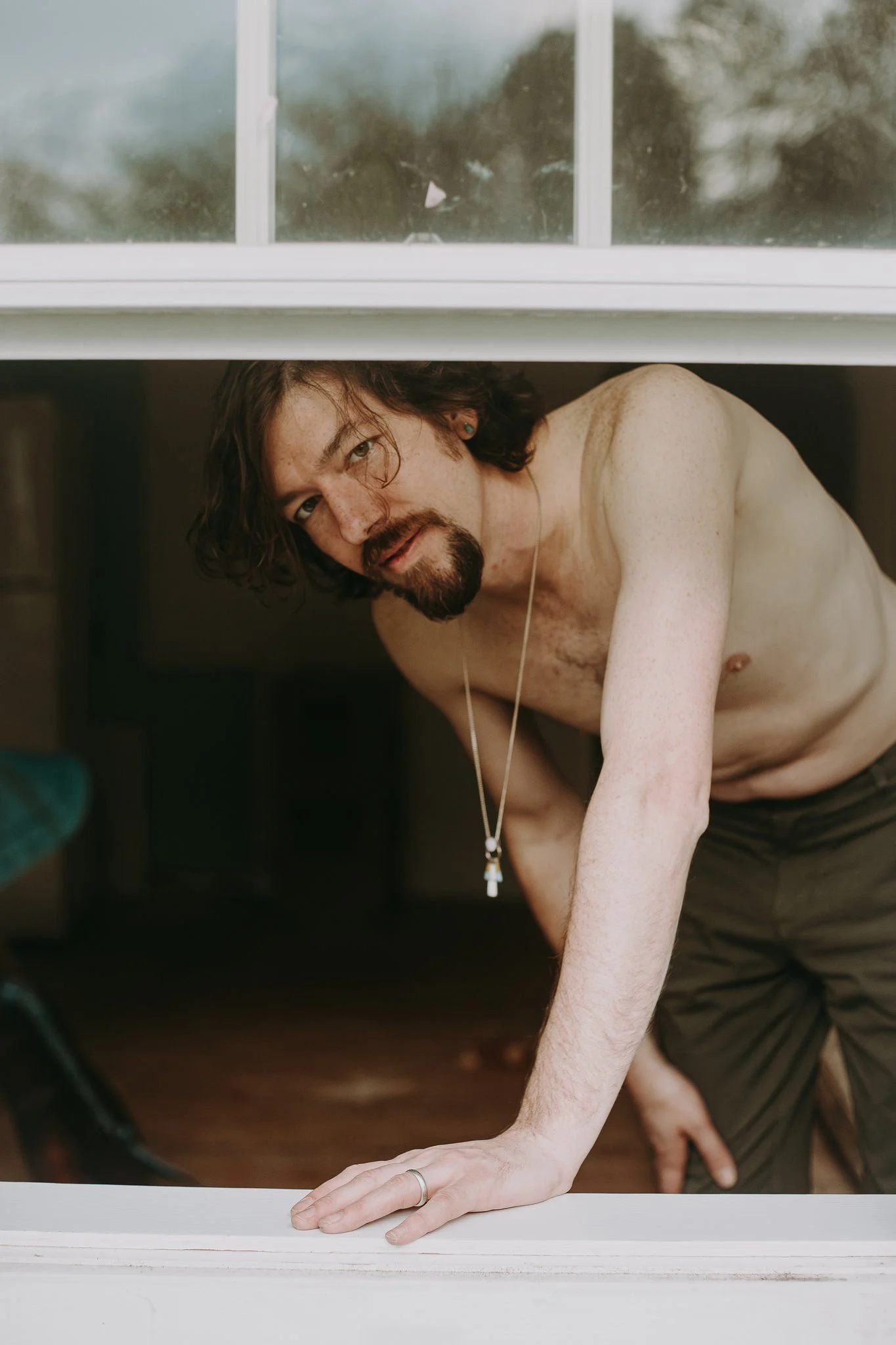 A person leaning out an open window with one hand on the windowsill