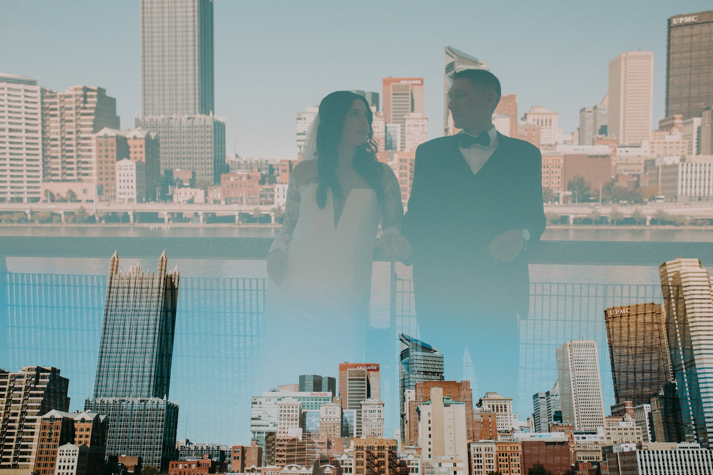 A city skyline with a faded image of a newlywed couple leaning on a railing in the middle 
