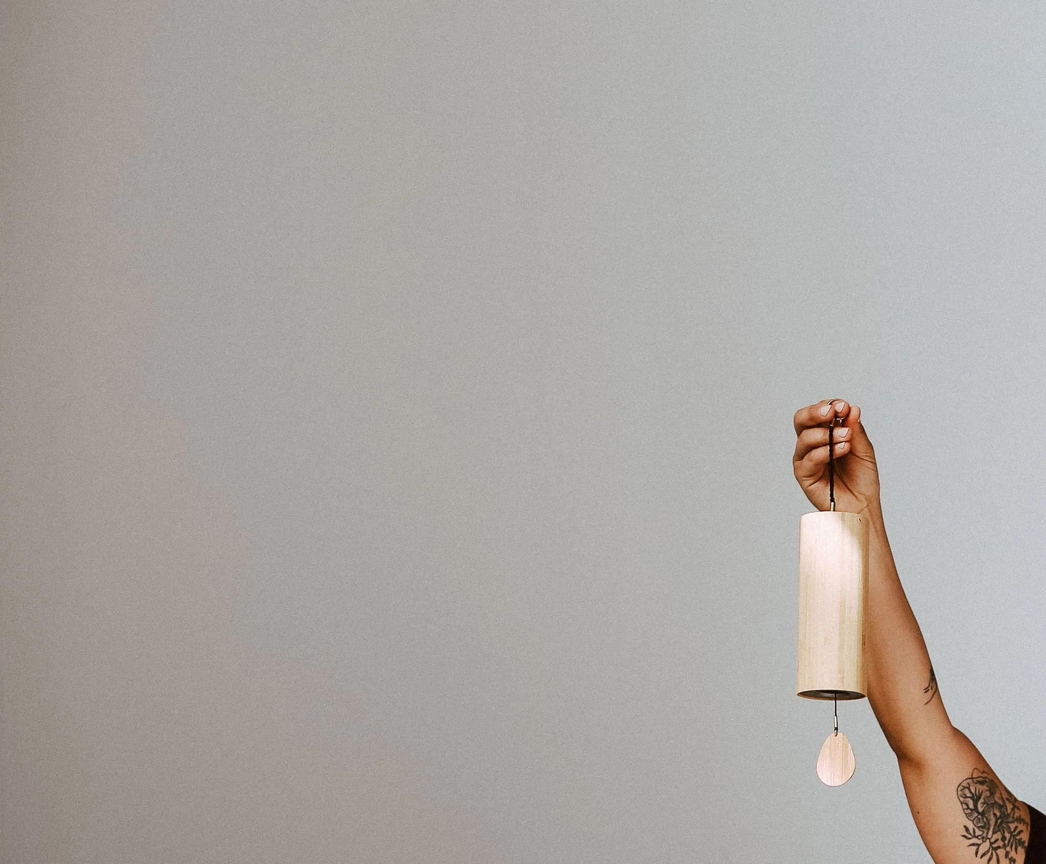 A person holding up a small wind chime 